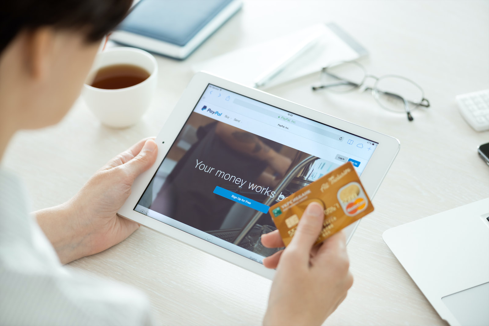 Person looking at a tablet computer, about to make a purchase with a credit card